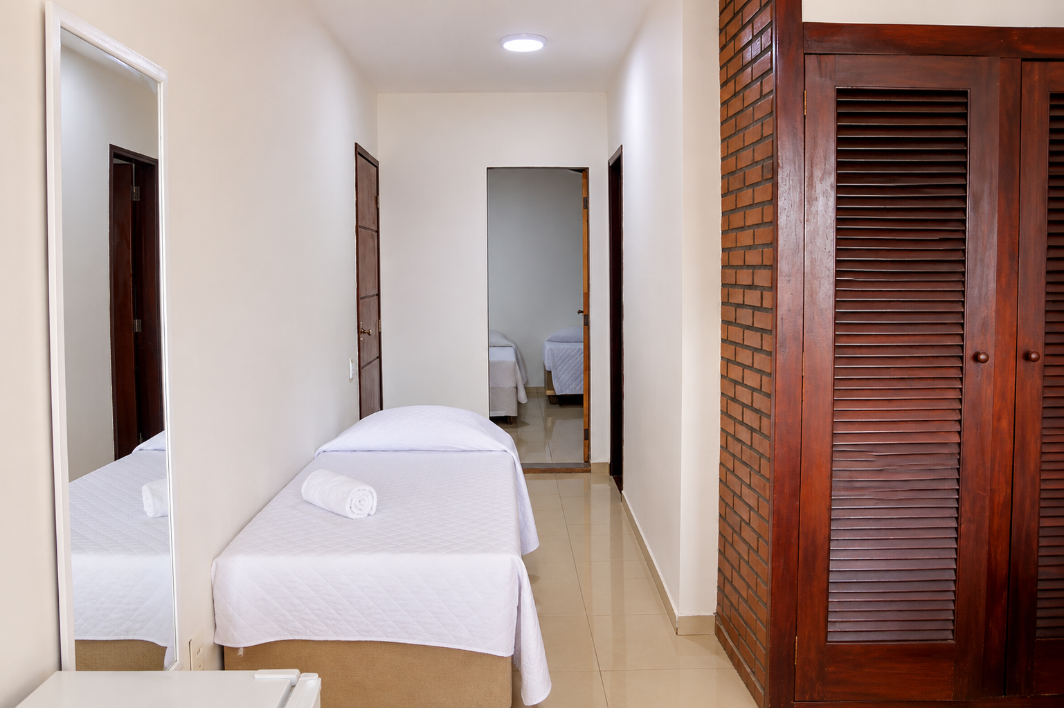 Corredor do apartamento familiar com cama de solteiro e armário de madeira
