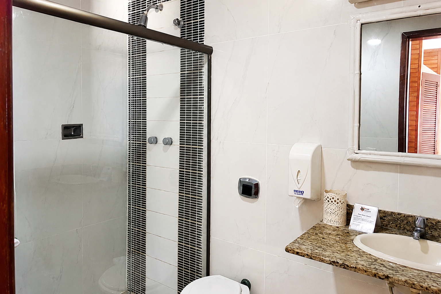 Banheiro do quarto com box de vidro e bancada de granito
