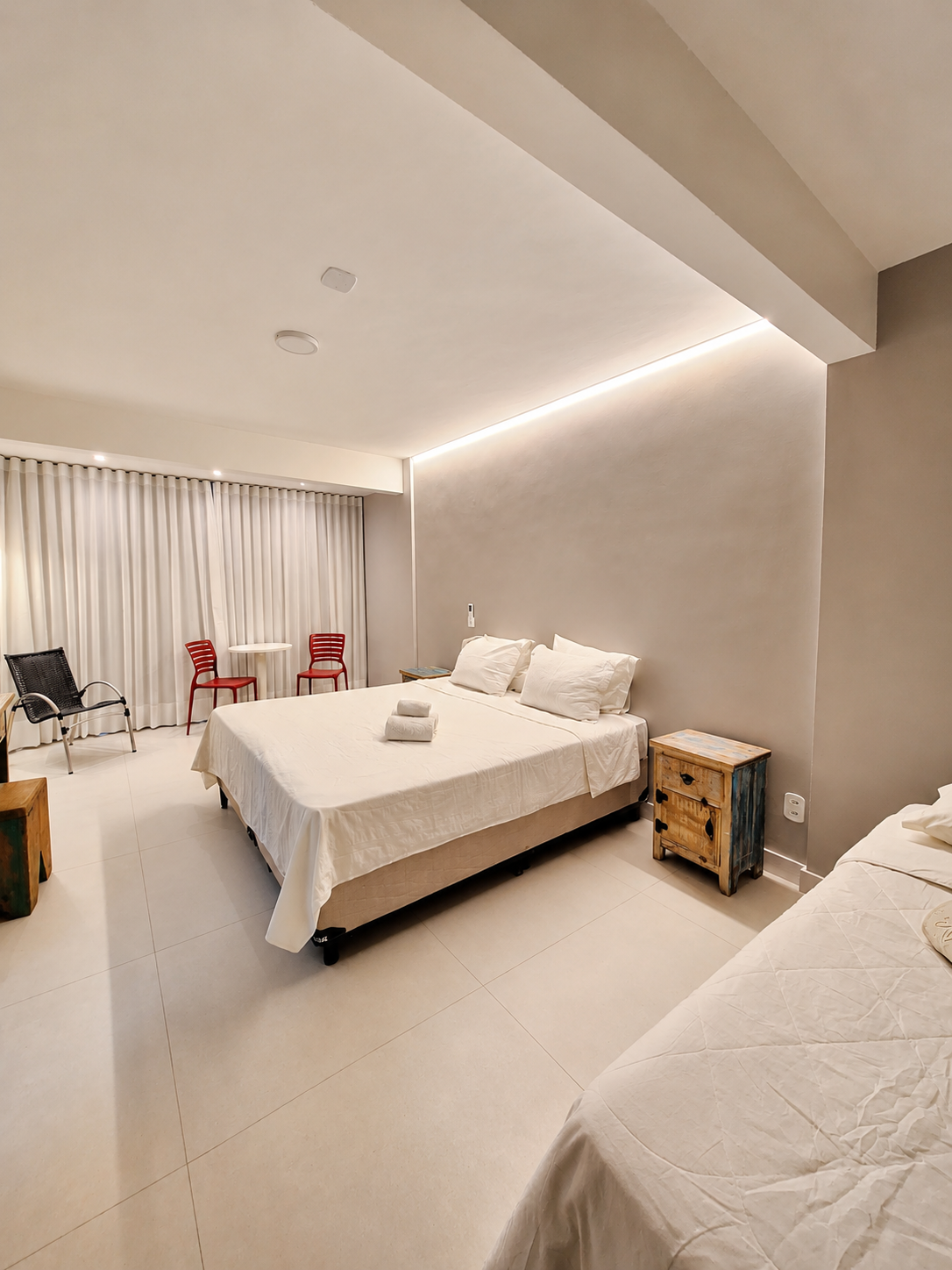 Cama de casal da Suíte Deluxe com mesa e cadeiras junto à janela