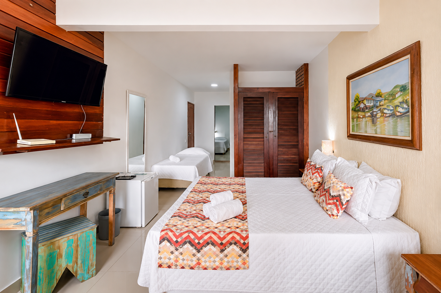 Quarto familiar com cama de casal, TV e cama de solteiro ao fundo